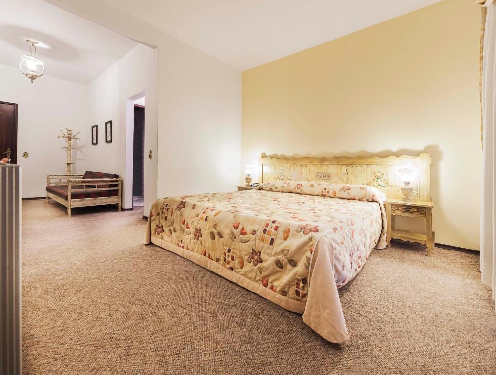 Quarto espaçoso do Hotel Tannenhof, com uma cama grande de casal, sofá e cabideiro