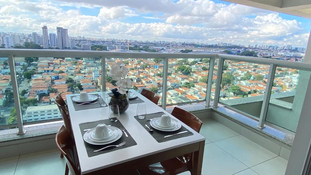 Mesa na sacada de um dos airbnb em São Paulo, com vista para a cidade, e com um jogo de jantar em cima.