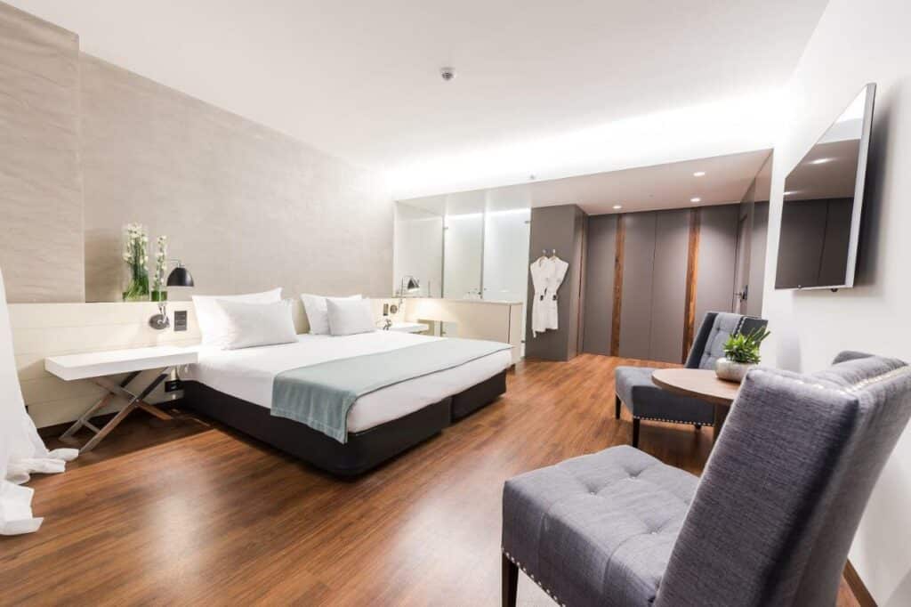 Quarto espaçoso no Lux Lisboa Hotel, com cama de casal, poltronas e TV plana
