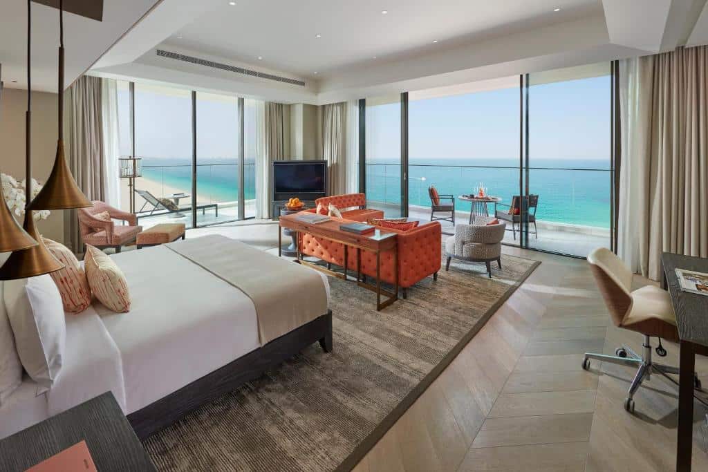 Quarto do Mandarin Oriental Jumeira, com cama, sofá, mesa de trabalho, poltronas e janelas com vista do mar