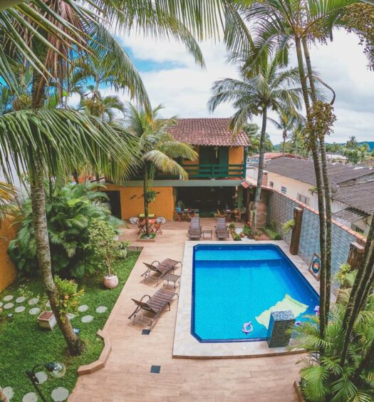 Imagem aérea do Cantinho do PE com uma piscina cercada por coqueiros