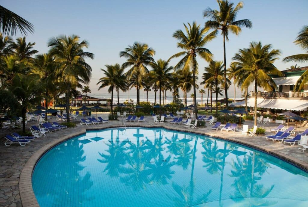 Piscina da Casa Grande Hotel Resort & Spa com vista para a praia, cercado por árvores e espreguiçadeiras