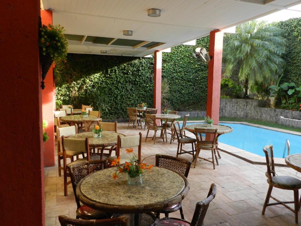 Vista da área de lazer com mesas e piscina no Eldorado Inn, em Feira de Santana.