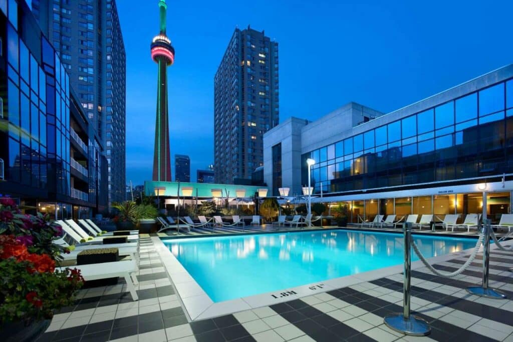 Piscina do Radisson Blu Downtown Toronto com um deck cercado por espreguiçadeiras e com vista para a cidade