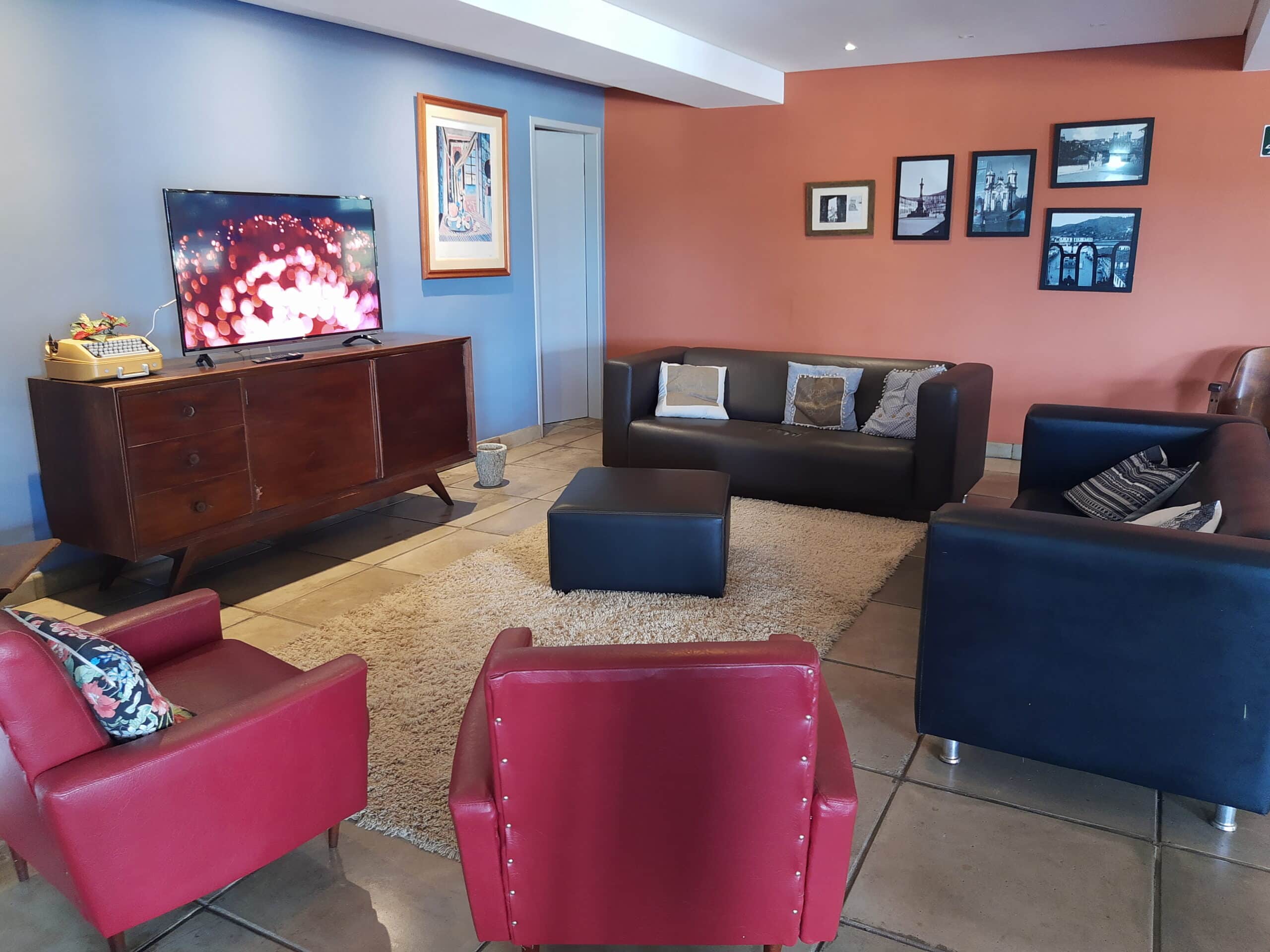 lounge compartilhado da pousada dos ofícios com sofás, poltronas e um hack com TV de tela plana tocando música