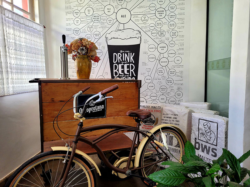 bicicleta decorativa ao lado de uma bancada em frente a uma parede pintada com desenhos sobre cerveja