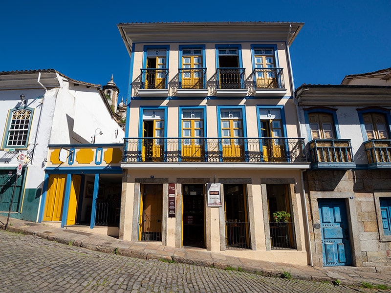 fachada do prédio colonial da pousada solar do ópera em ouro preto com portas e janelas pintadas em azul e amarelo