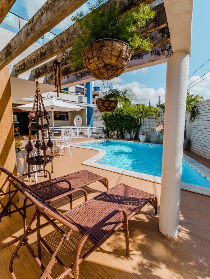Espaço de lounge compartilhado e piscina na Pousada Tropical Bessa com muitos lugares para sentar e decoração praiana
