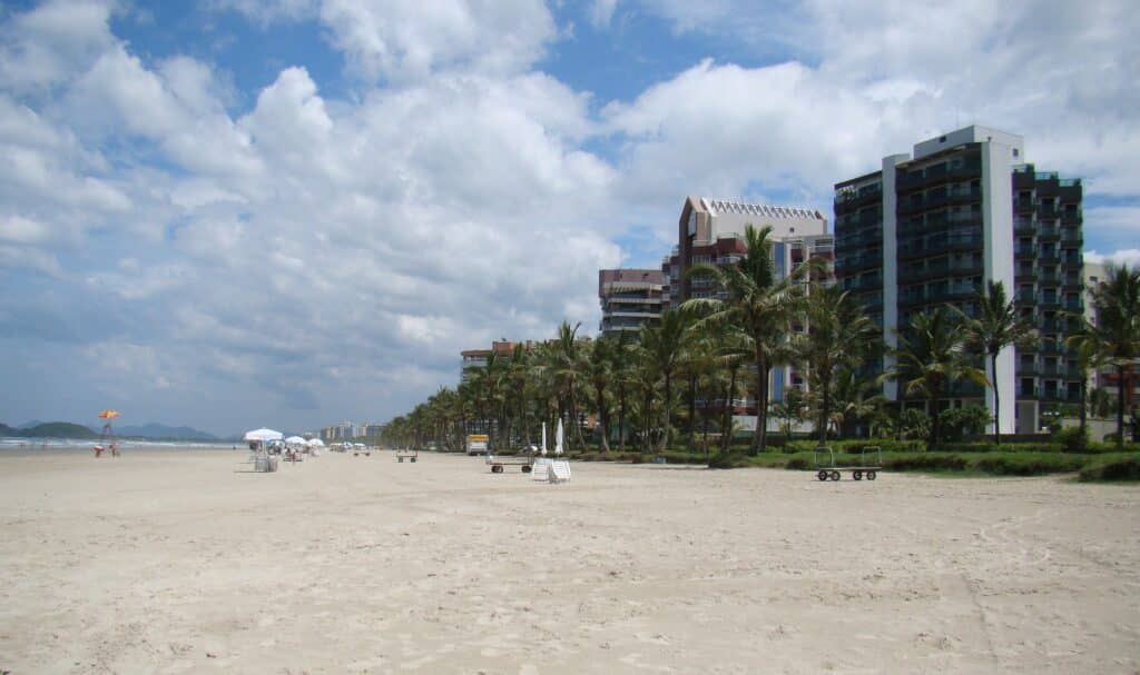 Praia de Riviera de São Lourenço, faixa de areia ampla com prédios e árvores ao redor
