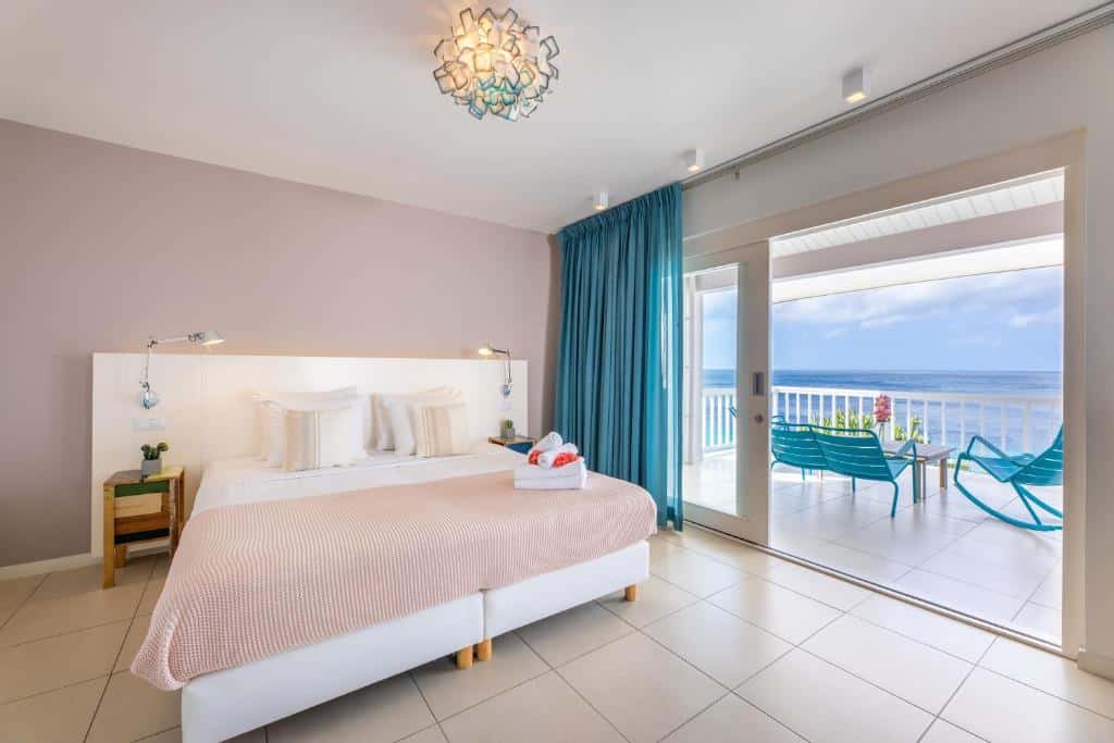 suíte do Coral Estate Luxury Resort com uma cama de casal e uma varanda com vista para o mar à direita