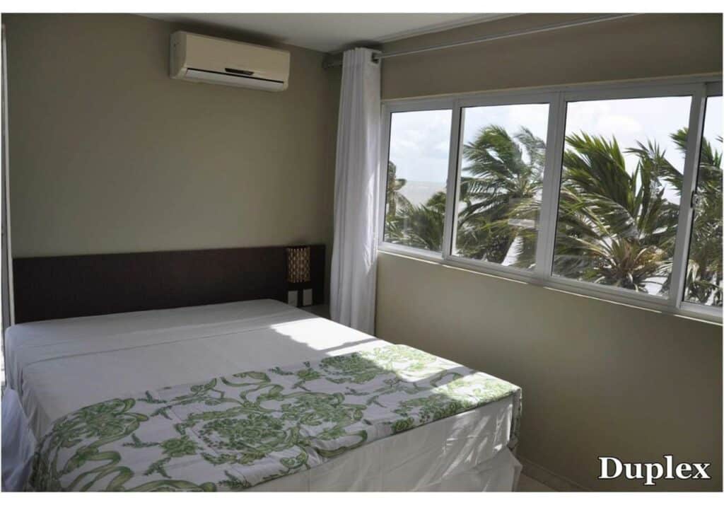 Quarto do Costa Brava Praia Hotel  com uma cama de casal e uma janela dando vista para a praia