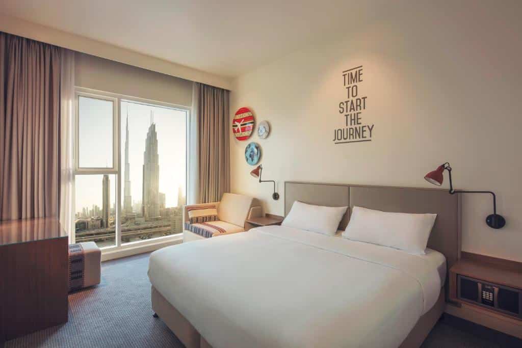 Quarto do Rove Downtown, um dos hotéis em Dubai, com cama de casal confortável e vista de uma torre pela Janela