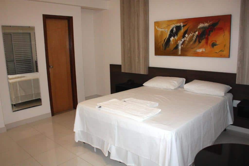 Quarto amplo no Executivo Hotel com uma cama de casal, um quadro e toalhas sob a cama