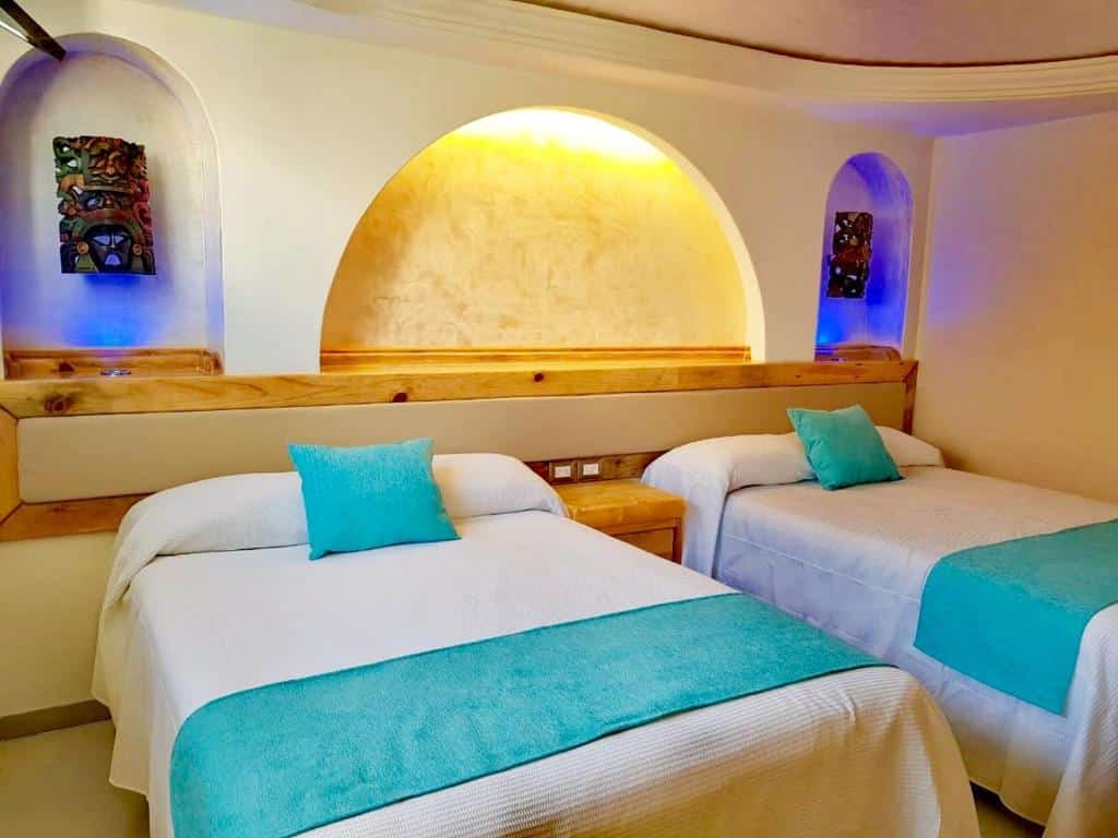 Quarto no Hotel Blue Star Cancun com uma cama de casal e uma de solteiro, com alguns itens de decoração e tudo em azul e branco