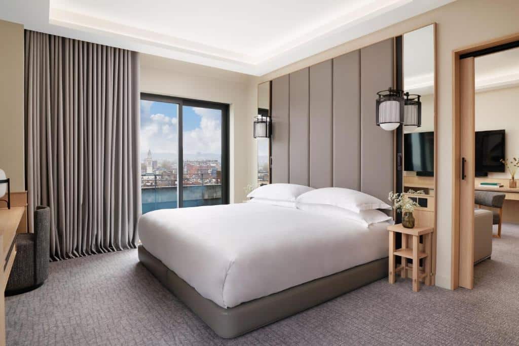 Quarto com varanda com vista para a cidade no Nobu Hotel Londres Portman Square com uma cama de casal, uma televisão, uma mesa e uma poltrona, ambiente elegante