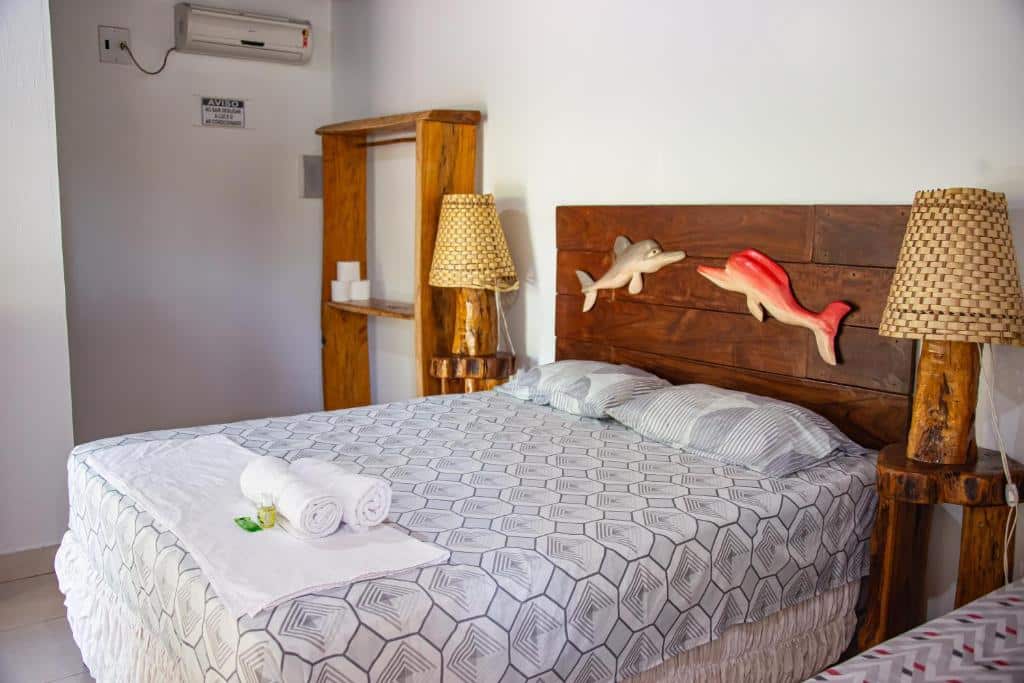Quarto da Pousada e Restaurante Amazonia com uma cama de casal, dois travesseiros, algumas toalhas sob a cama, dois abajures e itens de decoração rústicos, para representar pousadas em Alter do Chão