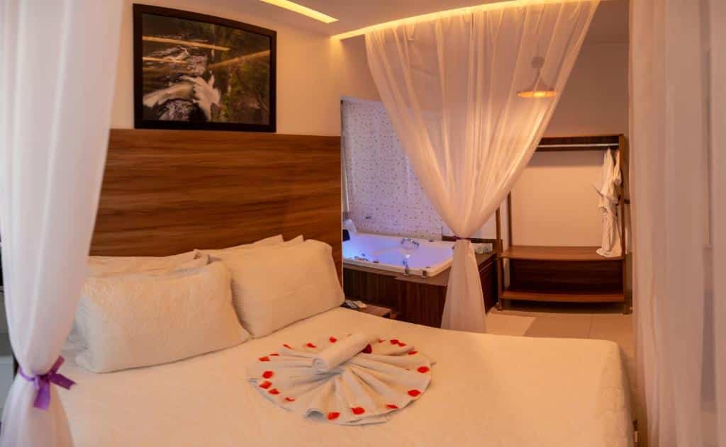 Quarto na Pousada Araras com cama estilo bangalô, com toalhas e detalhes de pétalas de rosa sob a cama, para representar pousadas na Chapada dos Veadeiros