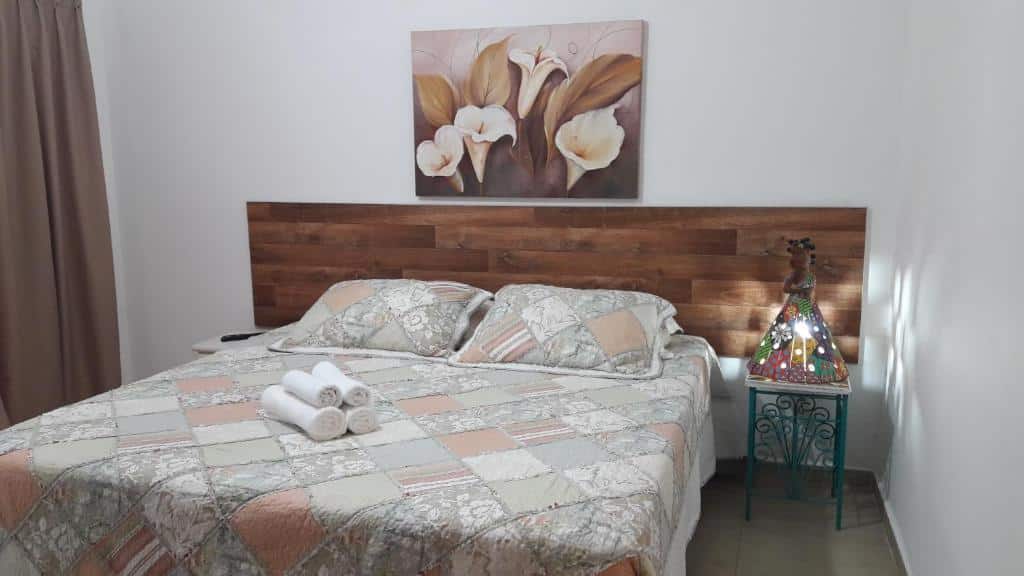Quarto na Pousada Villa Virgínia Guarujá com uma cama de casal, com travesseiros e toalhas sob ela, e uma luminária artesanal