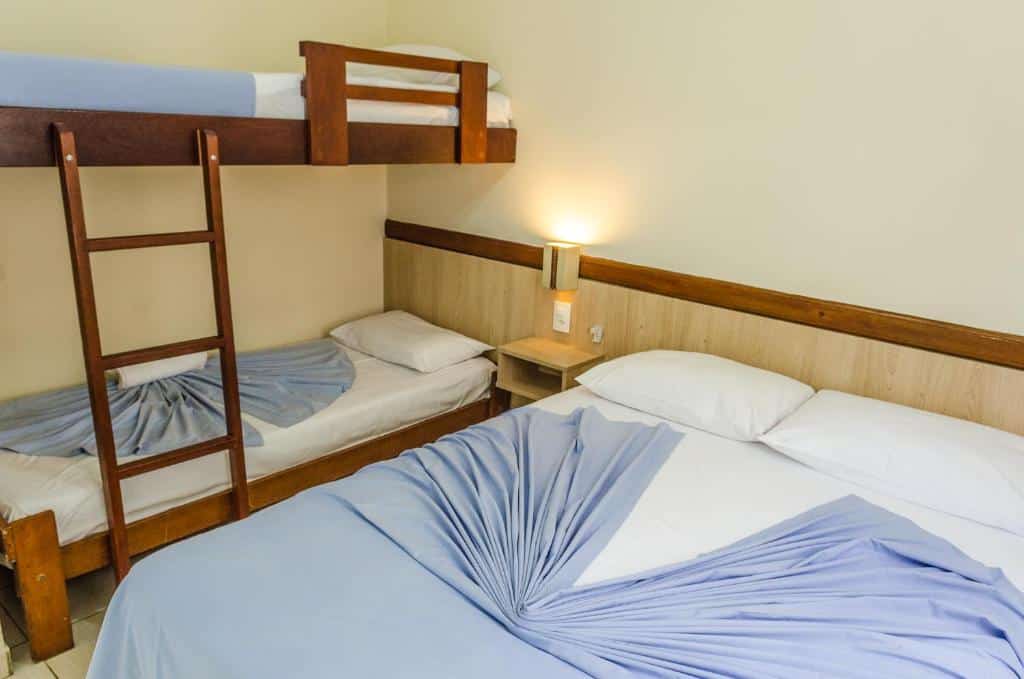 Quarto com cama de casal e uma cama de beliche na Pousada Vila da Praia.