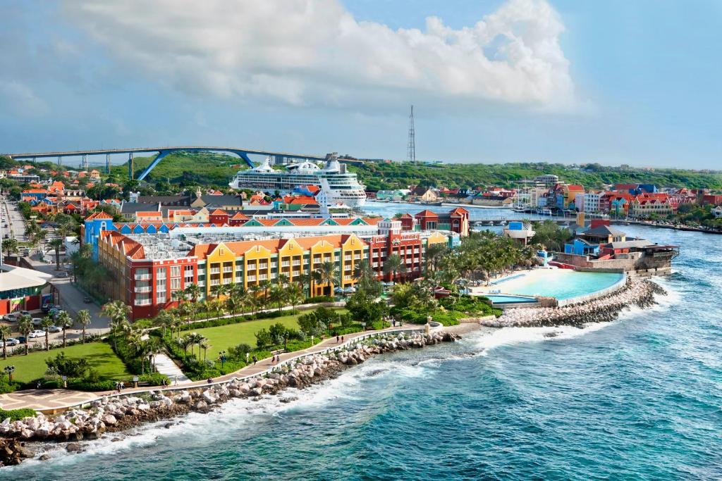 vista frontal do Renaissance Wind Creek Curacao Resort com prédios coloridos em frente ao mar agitado e azul
