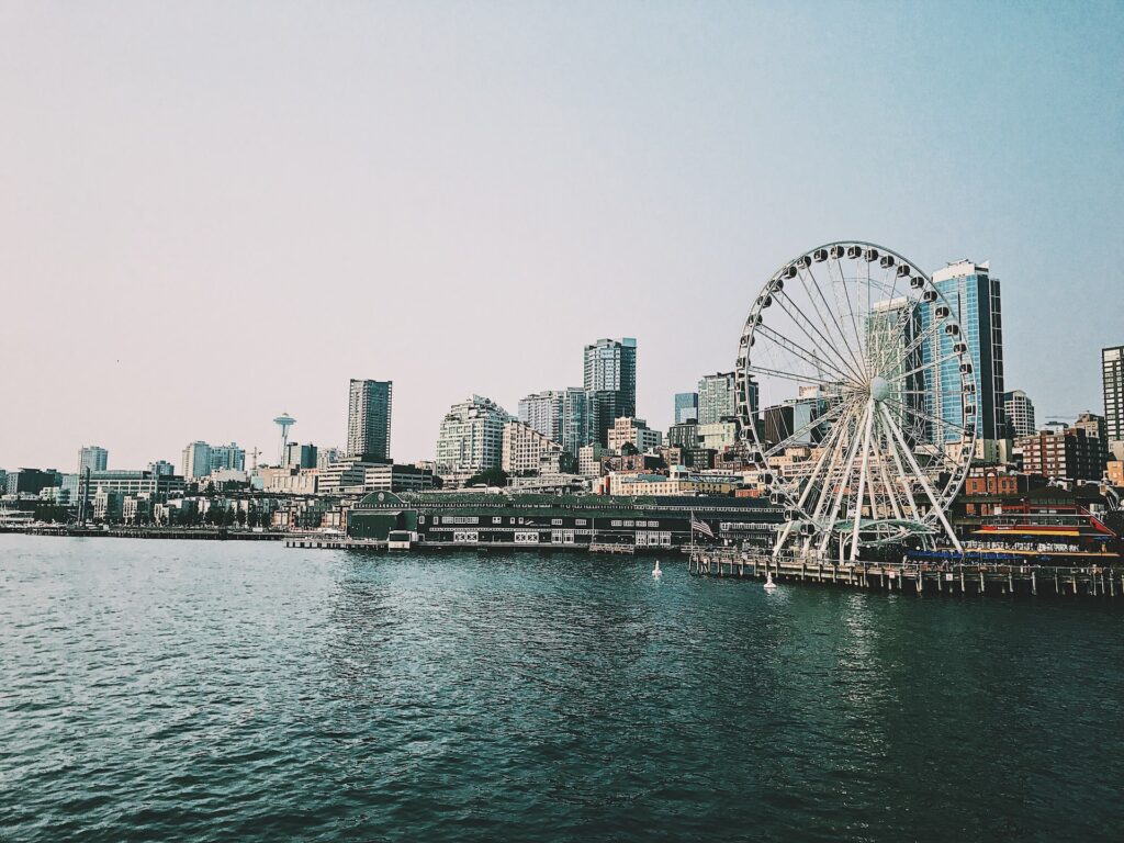 Alaskan Way em Seattle nos EUA, roda gigante, prédios e um oceano azul para representar o seguro viagem Seattle.