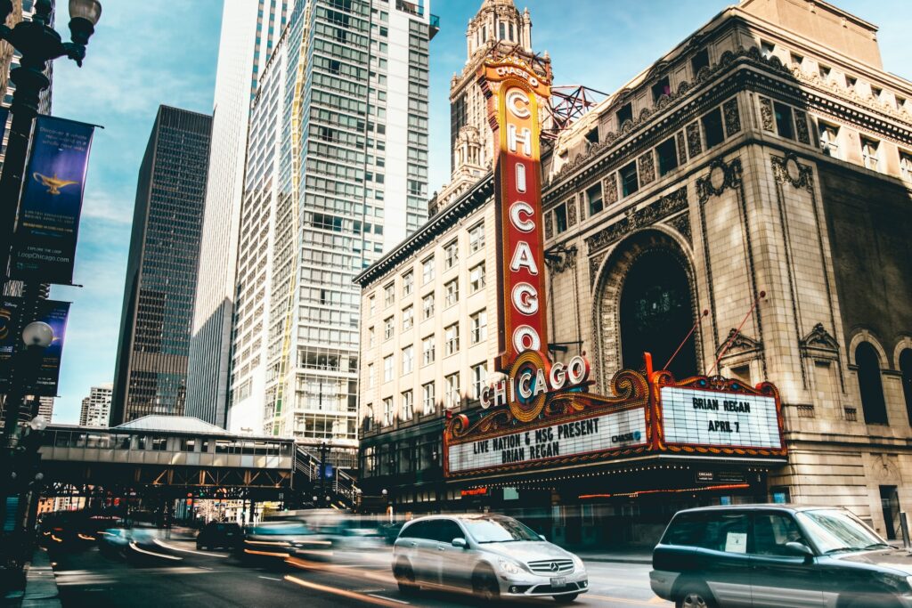 Teatro de chicago com prédios ao lado durante o dia com carros em movimento ilustrando post de seguro viagem chicago