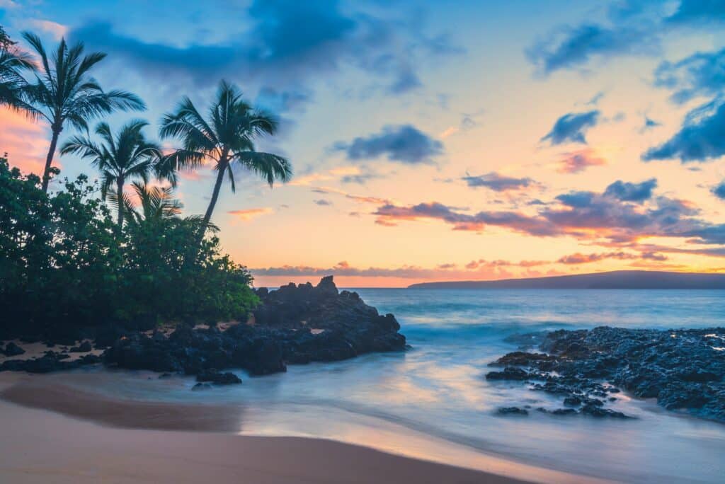 Secret Cove Beach Kihei em Maui no Havaí, céu com nuvens, oceano azul, palmeiras em volta e uma pequena faixa de terra para representar o seguro viagem Havaí.