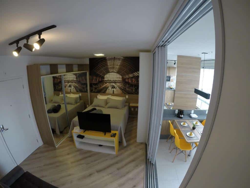 Interior de um dos airbnb em São Paulo. Quarto com cama, guarda roupa espelhado e varanda com mesa e balcão