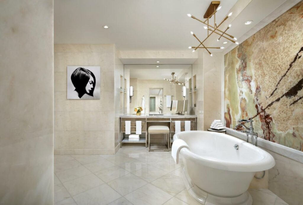 Banheiro amplo no The Ritz-Carlton com uma banheira, com toalhas e itens de decoração ao redor, incluindo um lustre