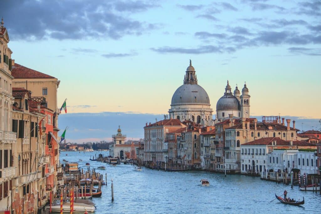 Canal de Veneza com algumas embarcações e muitos prédios históricos