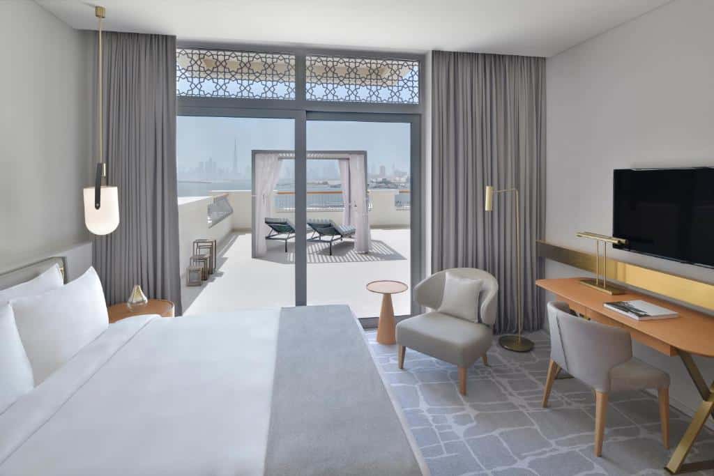 Quarto do Vida Creek Harbour, um dos hotéis em Dubai, com cama, e varanda com espreguiçadeiras e vista do mar