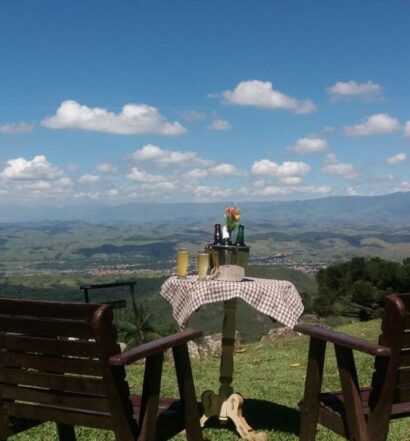 Duas cadeiras de madeira e uma pequena mesa com bebidas viradas para a serra e as montanhas em Itatiaia