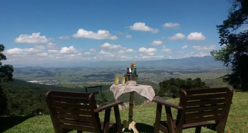 Duas cadeiras de madeira e uma pequena mesa com bebidas viradas para a serra e as montanhas em Itatiaia