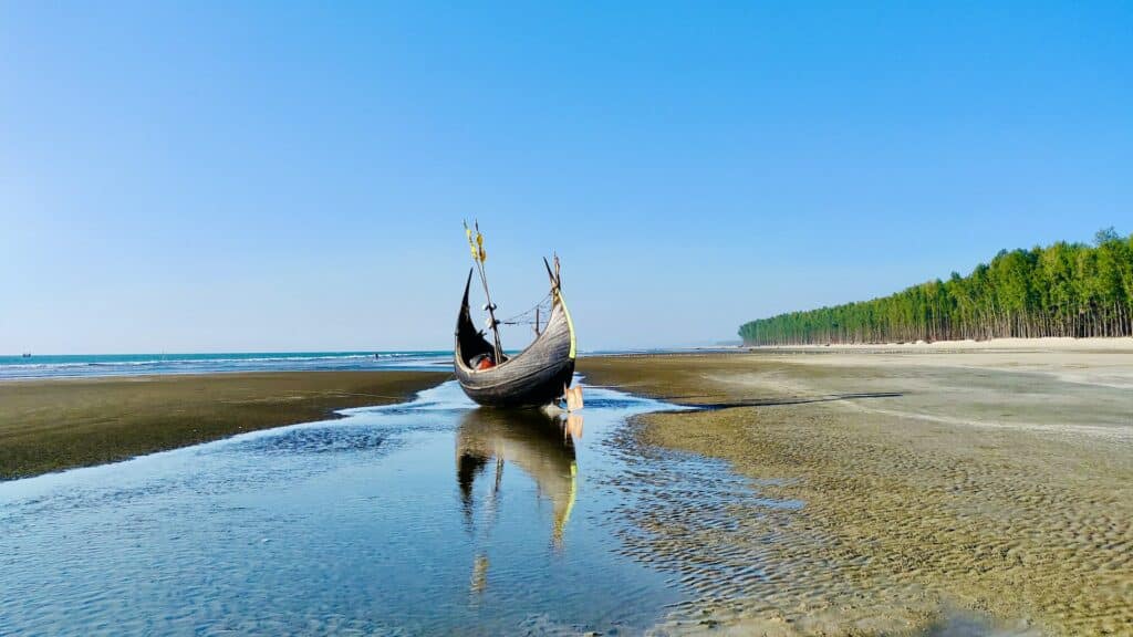barco solitário com extremidades alongadas em uma praia em Cox's Bazar que pode ser visitado com o seguro viagem Bangladesh
