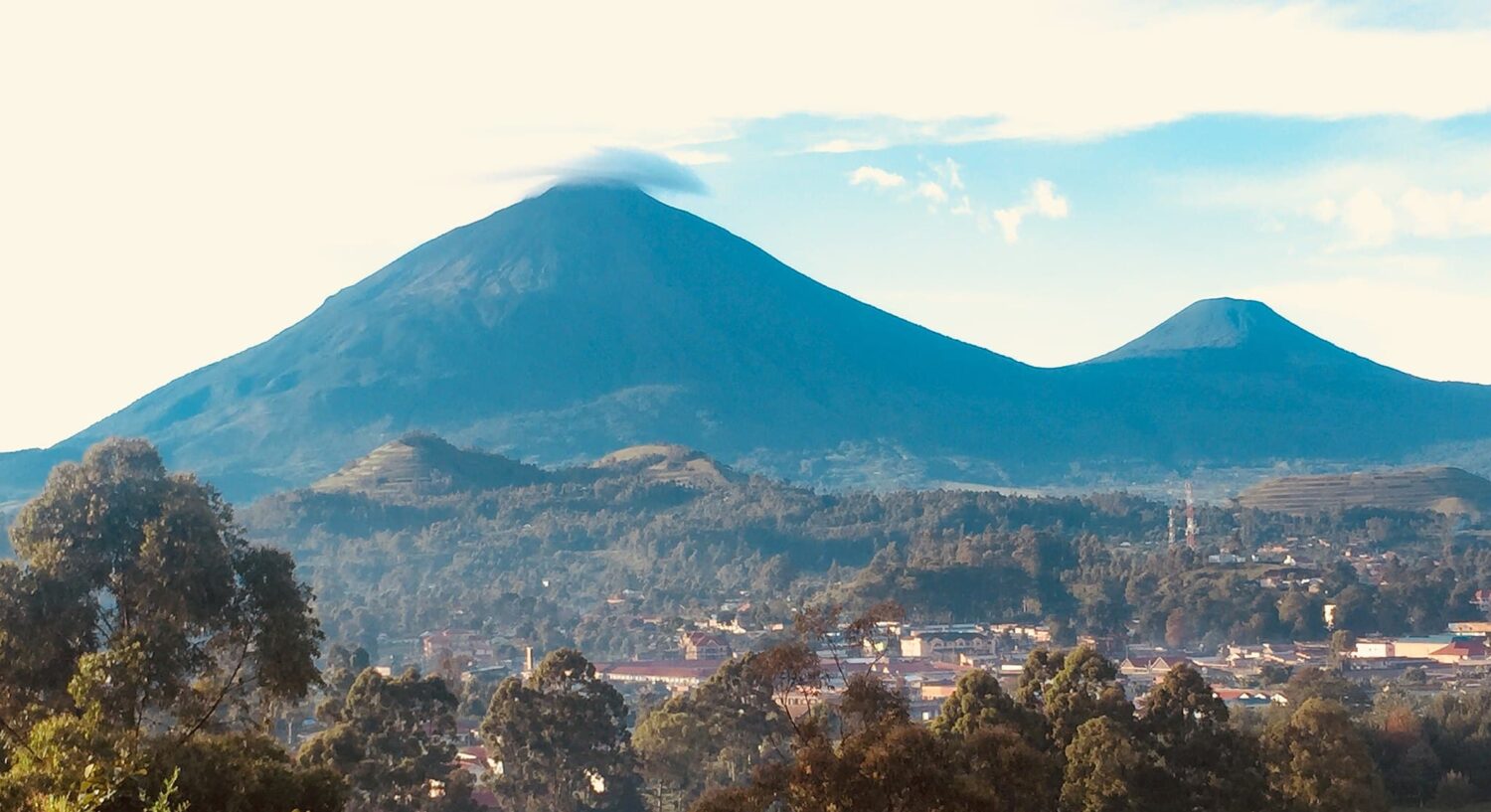 duas montanhas ao fundo de vegetações, o Vulcão Gahinga que pode ser visitado com o seguro viagem Ruanda