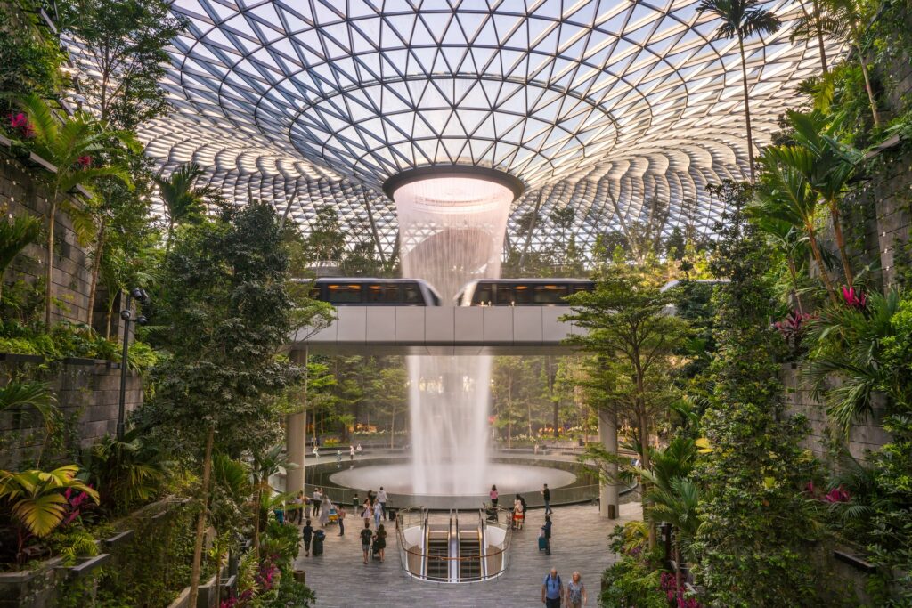 Cachoeira artificial com natureza exuberante ao entorno no aeroporto de Changi em Sinapura para representar o seguro viagem Singapura.