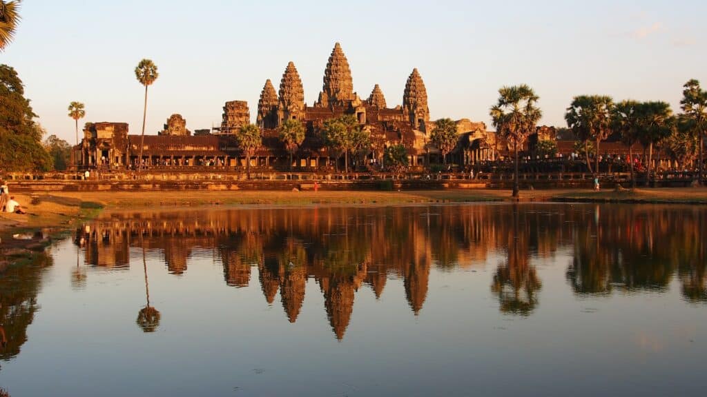 O maior templo do mundo com algumas árvores ao redor e em frente a um lago espelhado para ilustrar seguro viagem Camboja - Foto: Vicky T via Unsplash