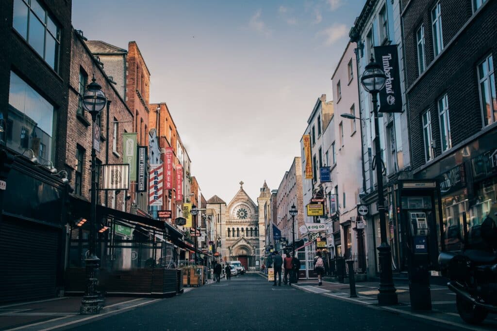 Anne Street em Dublin, com muitas lojas, pessoas andando na rua e uma igreja central ao fim da rua