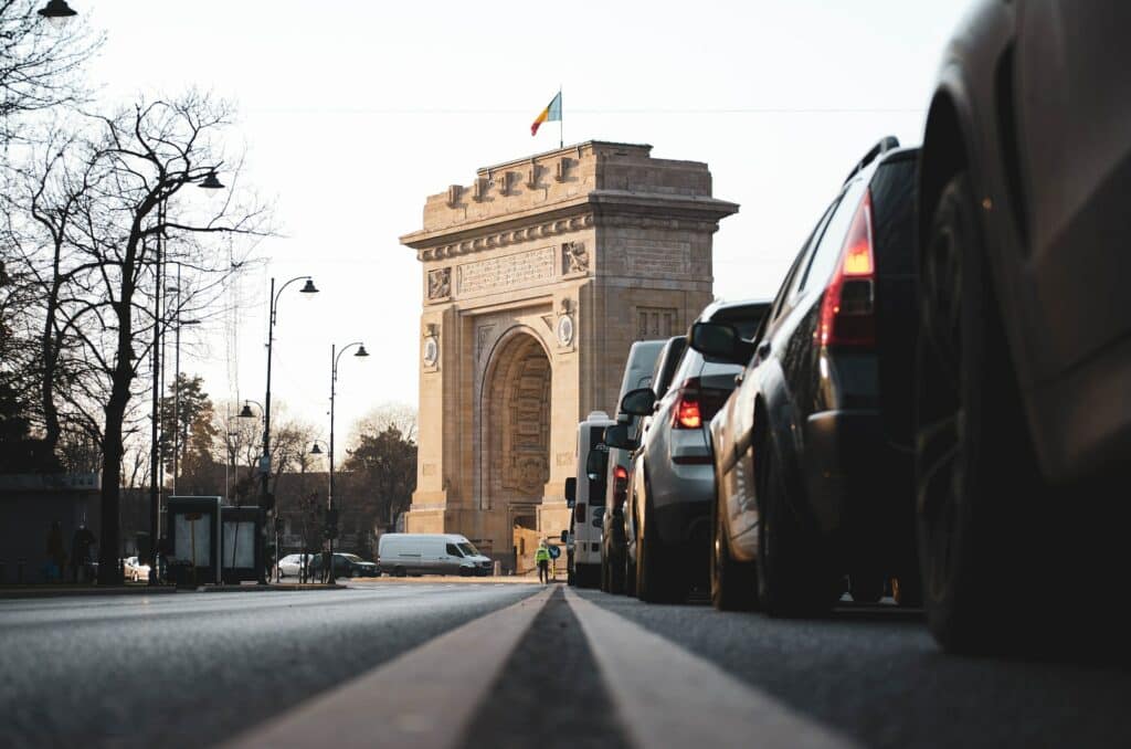 Via de tráfego com carros e acesso para a construção do arco do triunfo em Bucareste na Romênia para representar o seguro viagem Bucareste.