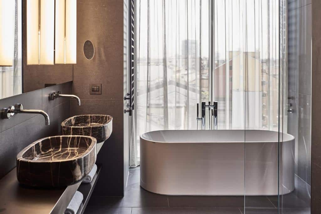banheira com vista para a cidade com duas pias em um decoração delicada, parecendo que estão flutuando no Hotel VIU Milan