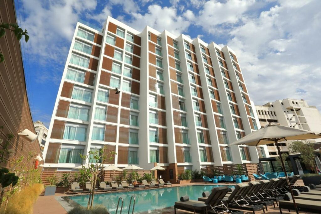 Foto do hotel Barceló Anfa Casablanca para o post seguro viagem Casablanca. São oito andares com uma piscina e cadeiras de praia na frente.