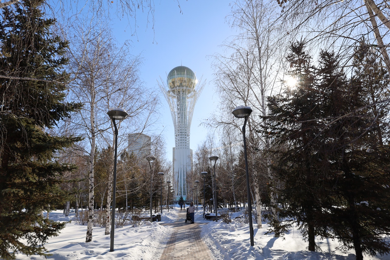 bayterek com árvores e neve ao fundo durante o dia ilustrando post seguro viagem Cazaquistão