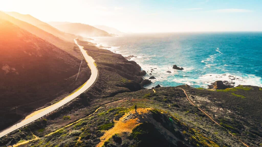 estrada Pacific Coast Highway beirando o mar sob um dia de céu claro e sol forte nos EUA