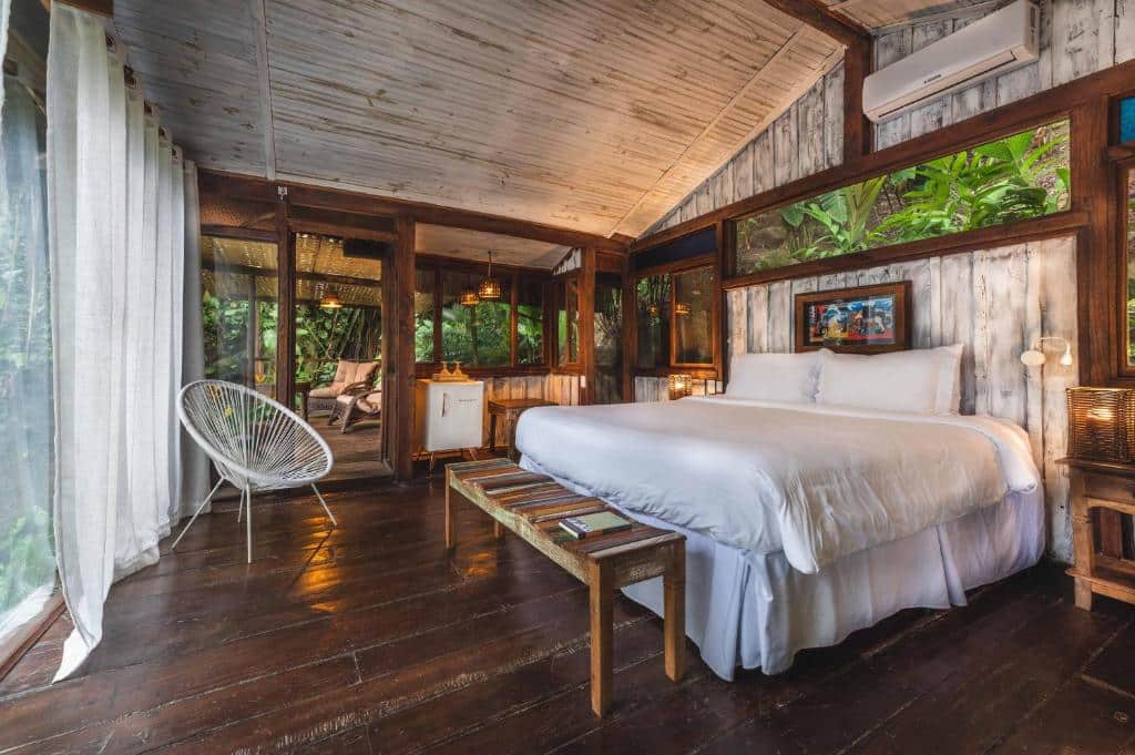 Quarto rústico na Casa Luz com tudo em madeira, uma cama de casal ampla, uma sacada grande, dois ambientes, cercado pelo verde da natureza