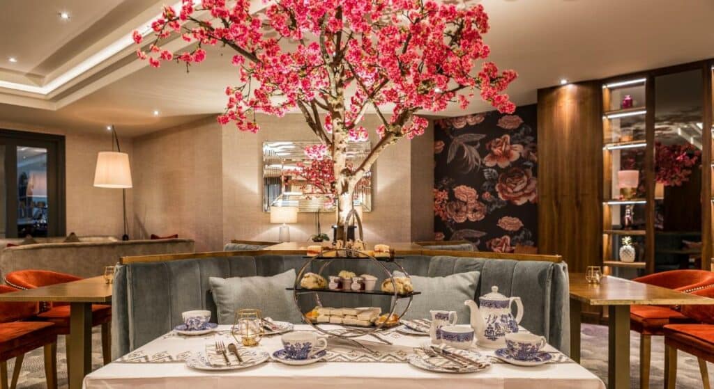 Local para refeições do Dublin Skylon Hotel com uma árvore que imita uma cerejeira, com uma mesa repleta de itens para um chá da tarde