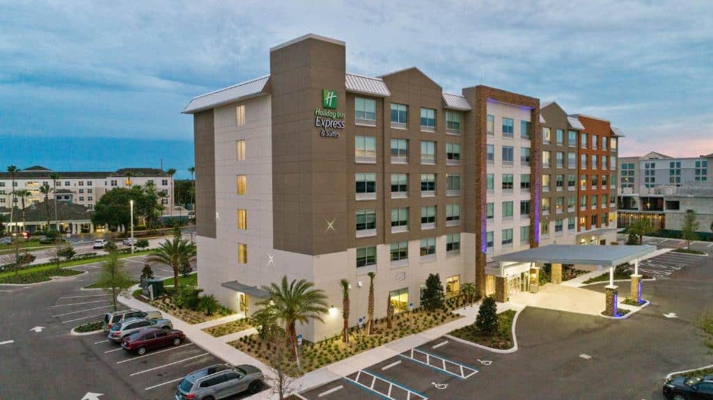 fachada em tons de marrom com várias janelinhas e estacionamento  do Holiday Inn Express & Suites Orlando- Lake Buena Vista, an IHG Hotel um dos hotéis em Orlando