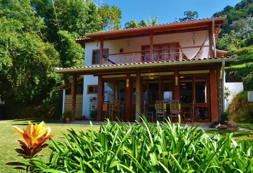 fachada com grama e uma florzinha amarela com redes e mesa de madeira em dois andares, uma das pousadas na Serra da Bocaina