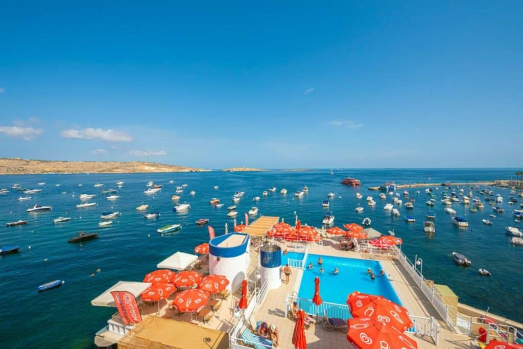 Piscina do Gillieru Harbour Hotel com vista direta para o mar cheio de barcos, para representar hotéis em Malta