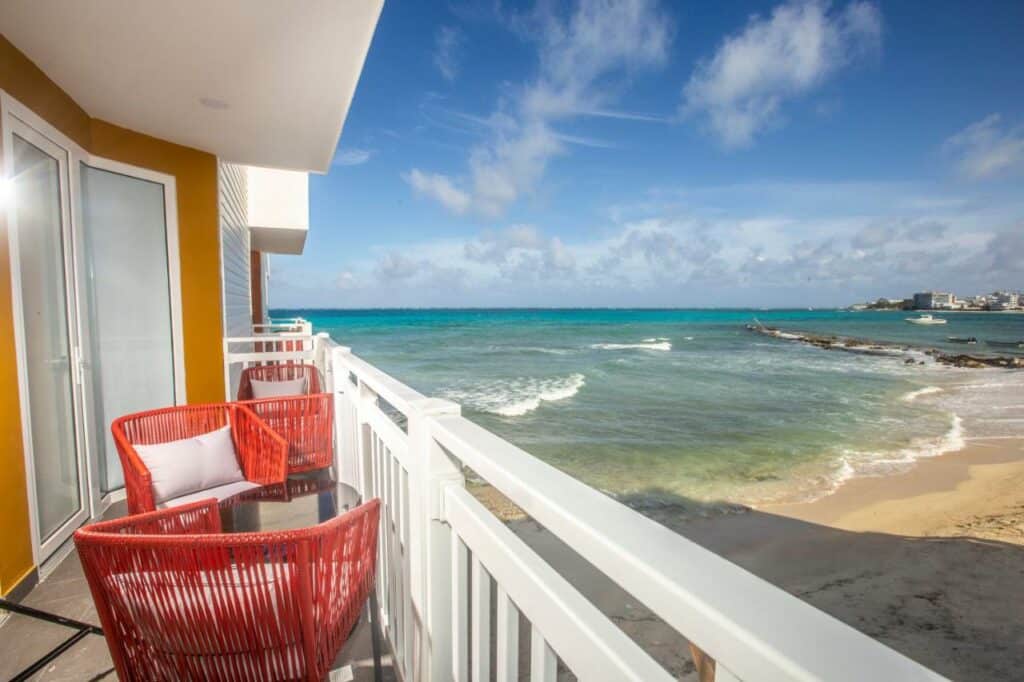 Varanda do Hotel Decameron Maryland All Inclusive com cadeiras vermelhas, e a varanda está virada diretamente para a praia, com a areia logo abaixo
