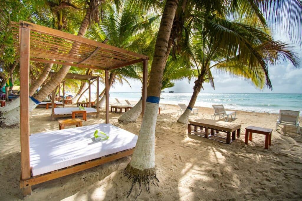 Cadeiras e camas estilo bangalô na areia da praia que são do Hotel Reina del Mar By Dorado de frente para o mar